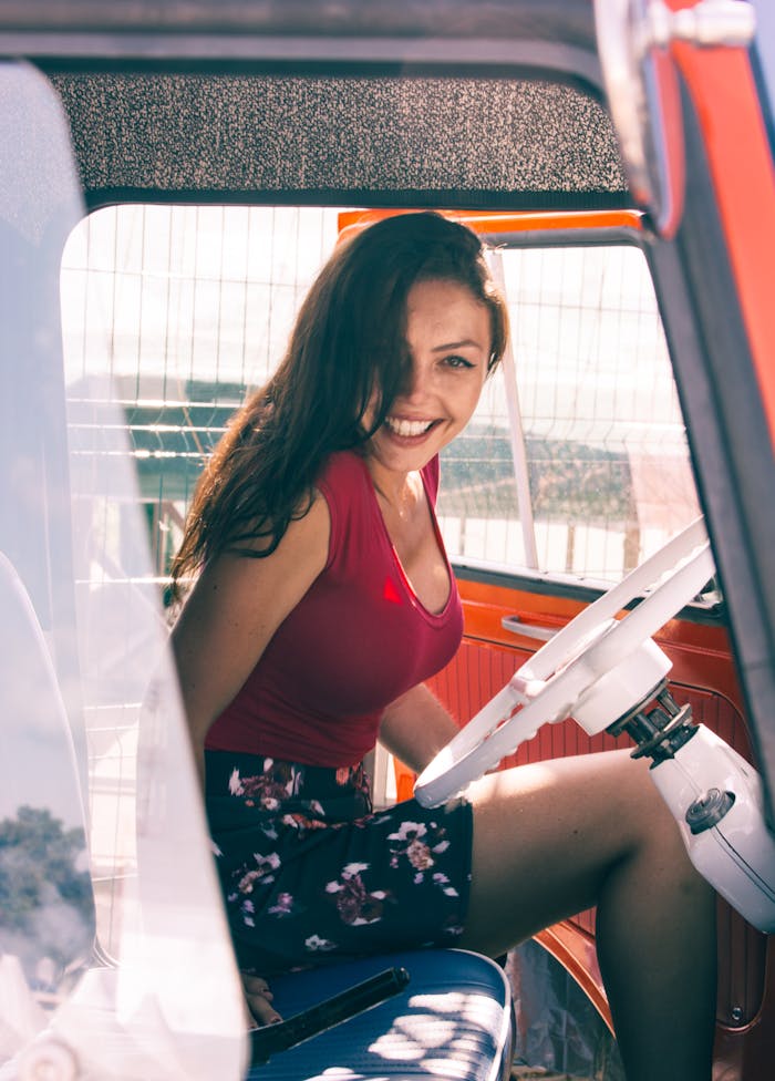 Young woman smiling inside a classic car, enjoying summer vibes.